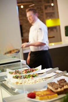 a man standing in front of a counter filled with plates and bowls full of food