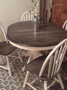 a dining room table with four chairs and a vase filled with flowers on top of it