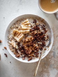 a bowl of oatmeal with bananas and nuts next to a cup of coffee