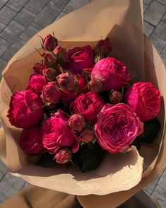 a bouquet of pink roses sitting on top of a brown paper wrapped in wax paper