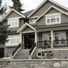 a house with stone walls and trees in the front yard, on a cloudy day