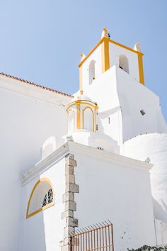 a white and yellow building with a clock on it's side