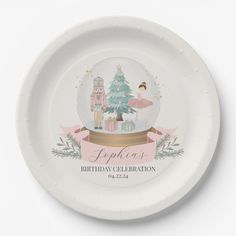 a paper plate with a snow globe on it that says happy birthday celebration in front of a christmas tree