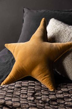 a yellow star pillow sitting on top of a bed next to two white and black pillows