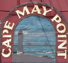 a sign that says cape may point on it's front door, with a boat in the background