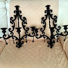 a black iron bed headboard with three candles on it and two pillows behind it