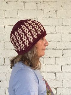 a woman wearing a red and white hat standing in front of a brick wall with her hand on her hip