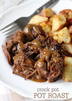 a white plate topped with meat and potatoes covered in gravy next to a fork