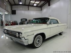 an old white car parked in a garage