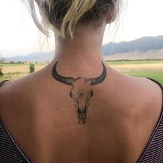 a woman with a cow skull tattoo on her back