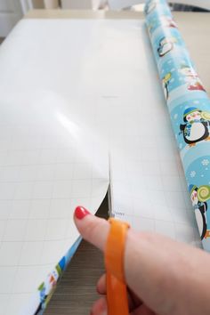 someone is cutting out the pattern for a penguin wrapping paper