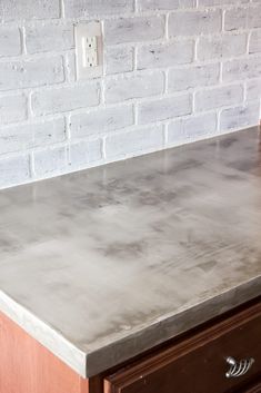 a kitchen counter top with drawers and a brick wall in the backgroung