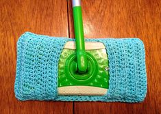 a close up of a mop on a wooden floor with a blue cloth and green handle