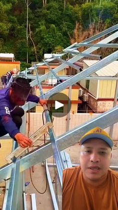 two men standing next to each other on top of metal structures