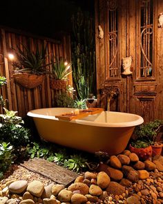 a bath tub sitting on top of a pile of rocks next to a wooden wall