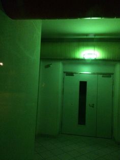 an empty room with two doors and green light on the ceiling in front of it