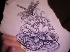 a person holding a piece of paper with a drawing of flowers and dragonflies on it