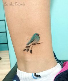 a small blue bird sitting on top of a tree branch with leaves around its neck