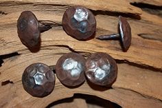 four metal buttons sitting on top of a piece of driftwood with nails sticking out of them