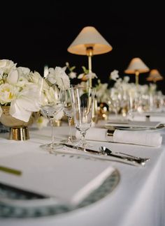 the table is set with white flowers and silverware