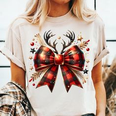 a woman wearing a t - shirt with a bow and reindeer antlers on it