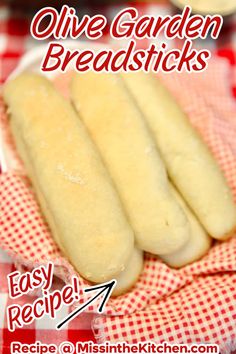 three breadsticks sitting on top of a red and white checkered table cloth