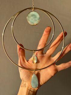 a woman's hand is holding onto a circular necklace with two pendants hanging from it