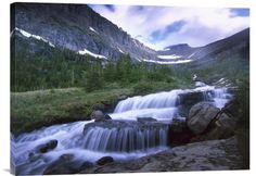 a waterfall in the mountains with snow on top