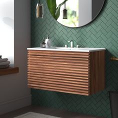 a bathroom with green wallpaper and a round mirror