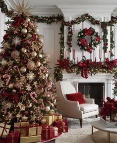 a living room decorated for christmas with red and gold decorations on the fireplace mantel