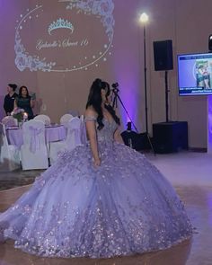 a woman in a ball gown standing on the dance floor at a formal event with people watching