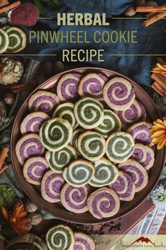 a plate full of cookies with purple and green swirls on top, surrounded by autumn leaves