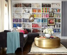 a living room filled with furniture and bookshelves covered in lots of colorful books