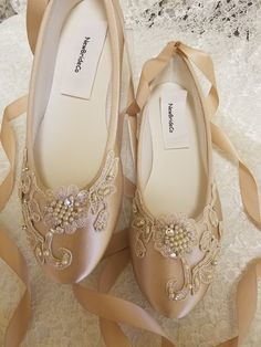 a pair of shoes that are on top of a lace table cloth with ribbons around them