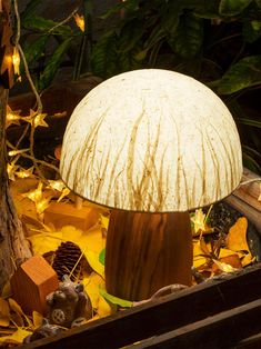 a mushroom lamp sitting on top of a pile of leaves next to a wooden box