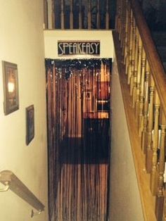 an open door leading to a stairway with stringy curtains hanging on the wall and wooden handrails