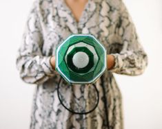 a woman holding a green object in her hands with an eyeball on it's center