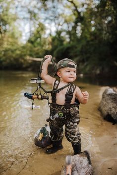 a little boy standing in the water with his fishing gear