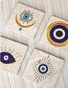 four coasters with different designs on them sitting on a wooden table next to each other