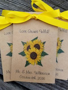 two tags with sunflowers on them are tied to a wooden table and the tag says love grows wild