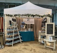 the tent is set up for an event with wine bottles on display and lights strung from the ceiling