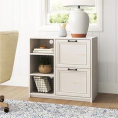 a white cabinet with two drawers next to a chair and lamp on top of it