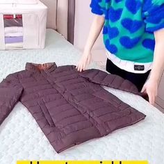 a woman is standing next to a bed with a jacket on it