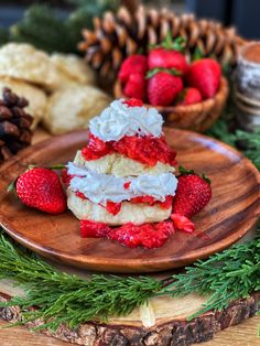 strawberries and whipped cream are on a plate next to pine cones, pine cones and other holiday decorations