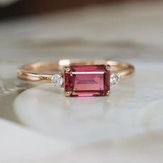 a pink tourmaline and diamond ring sitting on top of a table