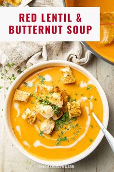 a bowl of red lentil and butternut soup with croutons on the side