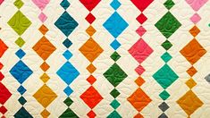 a multicolored quilt with diamond shapes on it