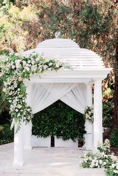 a white gazebo decorated with flowers and greenery