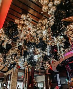 a room filled with lots of black and silver balloons hanging from the ceiling above it