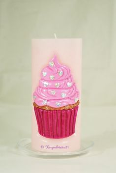 a pink cupcake candle sitting on top of a glass plate